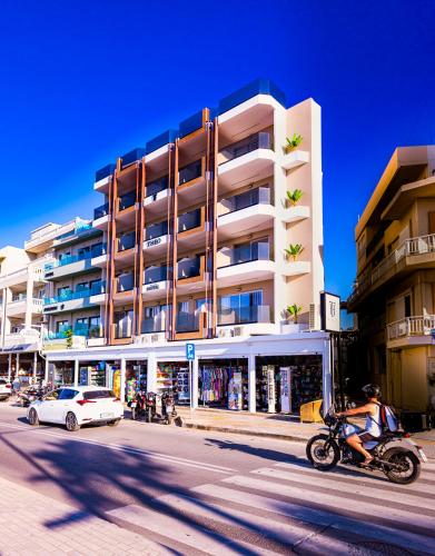 a man riding a motorcycle down a street in front of a building at Theo Beach Hotel Apartments in Rethymno Town