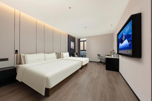 a bedroom with a large white bed and a flat screen tv at Atour Hotel Nantong Development Zone Aeon Mall in Nantong
