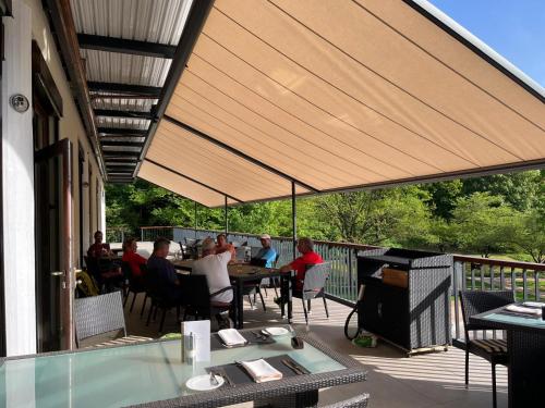 a group of people sitting at tables on a patio at Flair Park Hotel Ilshofen in Ilshofen