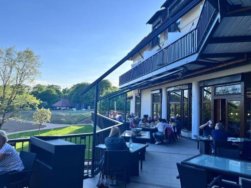 a group of people sitting at tables on a patio at Flair Park Hotel Ilshofen in Ilshofen