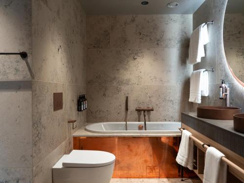 a bathroom with a tub and a toilet and a sink at Elite Hotel Frost - Hotel & Spa in Kiruna