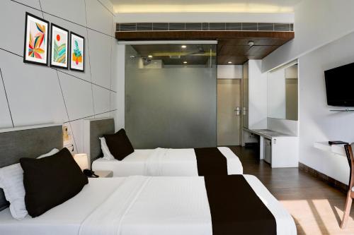 a hotel room with two beds and a television at Super Collection O Limda Chowk Formerly Hotel Harmony in Rajkot