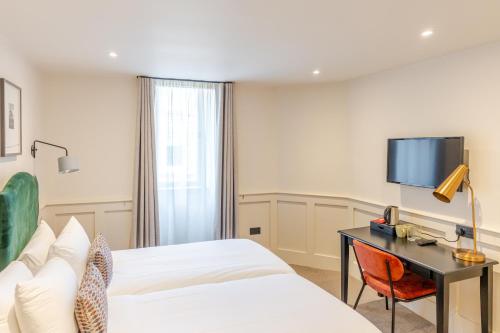 a hotel room with a bed and a desk and a tv at Grove House Hotel in Edinburgh