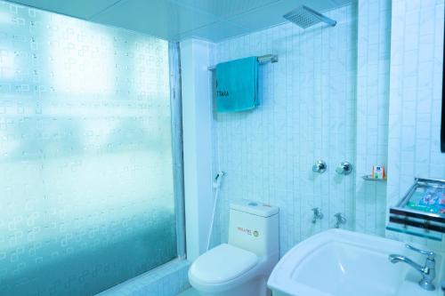 BāiljuriにあるHotel Uttaraのトイレとガラスドアのシャワーを備えたバスルーム