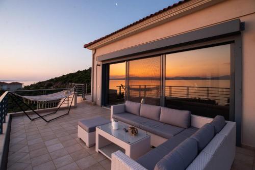 a couch on a balcony with a view of the ocean at Sea Whisper Villa Peloponnese in Arkadiko Chorio