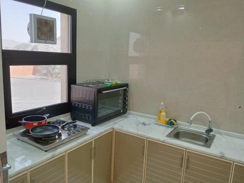 a kitchen with a microwave and a stove and a sink at Hatta Guest house Resort in Būbādī