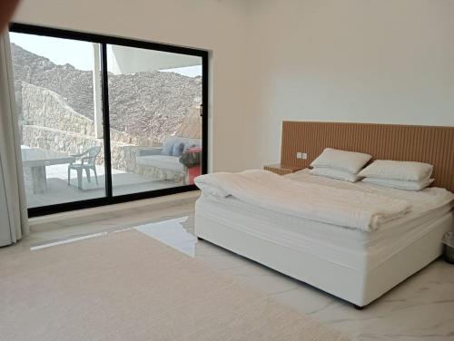 a bedroom with a large white bed and a balcony at Hatta Guest house Resort in Būbādī