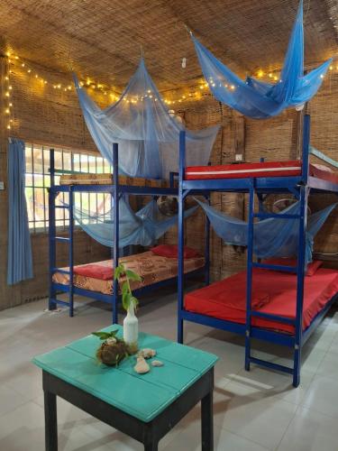 a room with three bunk beds and a table at CocoHuts in Koh Rong Sanloem