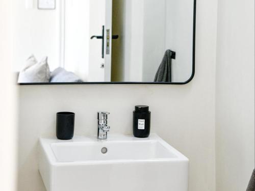 a bathroom with a white sink and a mirror at B&B At 66 Henderson in Claredon