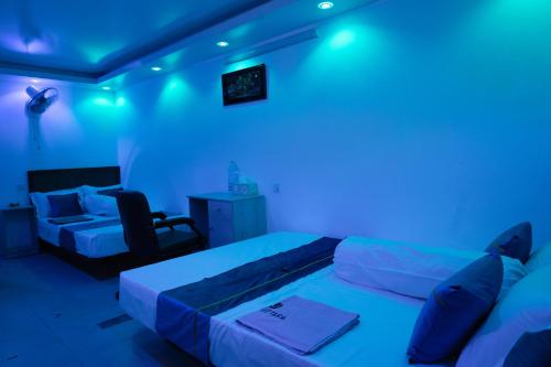 a room with two beds and a couch and blue lights at Hotel Uttara in Bāiljuri