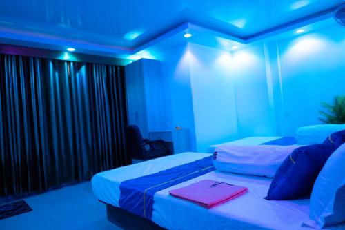 two beds in a room with blue lights at Hotel Uttara in Bāiljuri