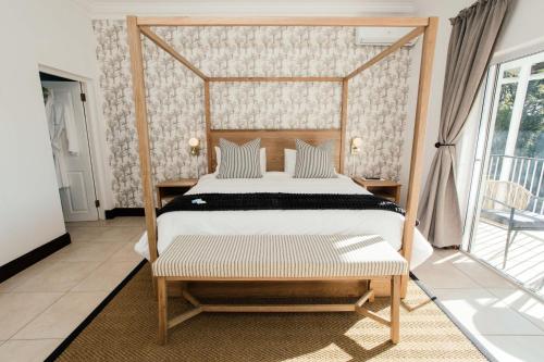 a bedroom with a canopy bed and a balcony at The Palms Boutique Hotel in Hilton