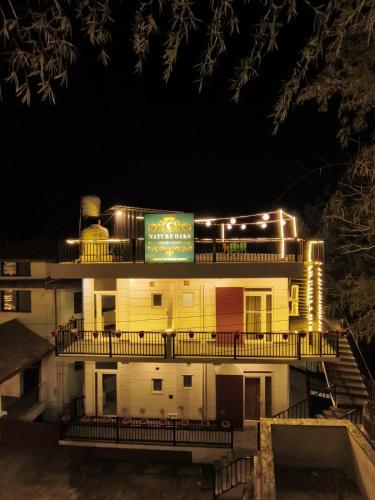 a building with a sign on top of it at night at Nature Oaks Luxury stayz Nainital in Bhīm Tāl