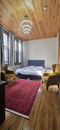 a bedroom with a bed and two chairs and a red rug at Grand Bedir in Istanbul