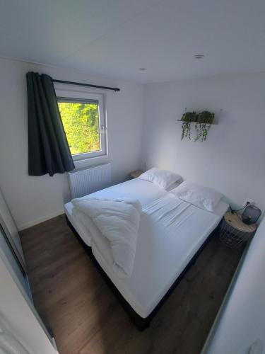 a bedroom with a white bed with a window at Fiets & Relax Chalet in Den Bommel