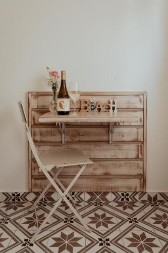 a table with a bottle of wine and a chair at Fészek -Étel és Hotel- in Zánka