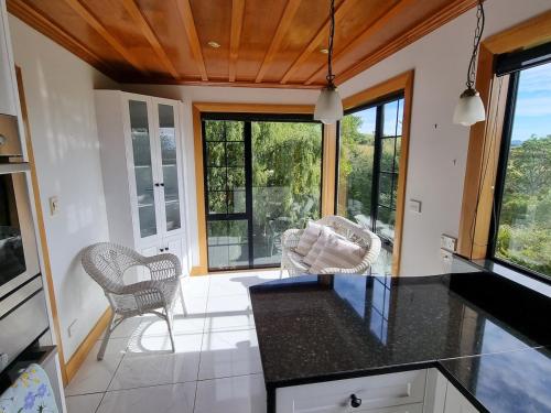 a kitchen with a counter and chairs and windows at Greenwood Homestead in Tarara
