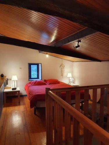 Cette chambre comprend un lit avec des draps rouges et un plafond en bois. dans l'établissement Family home with pool, à Saint-Lon-les-Mines