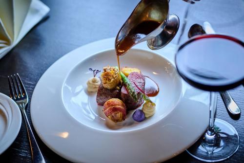 a plate of food on a table with a glass of wine at Hotel Wutzschleife in Rötz