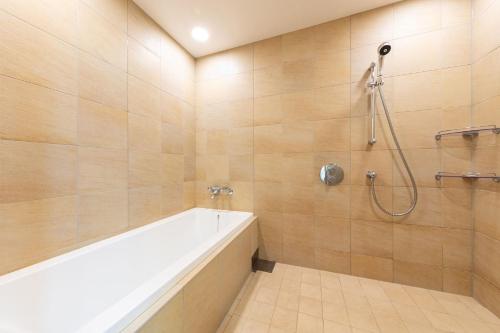 a bathroom with a bath tub and a shower at Spa Resort Hawaiians Monolith Tower in Iwaki