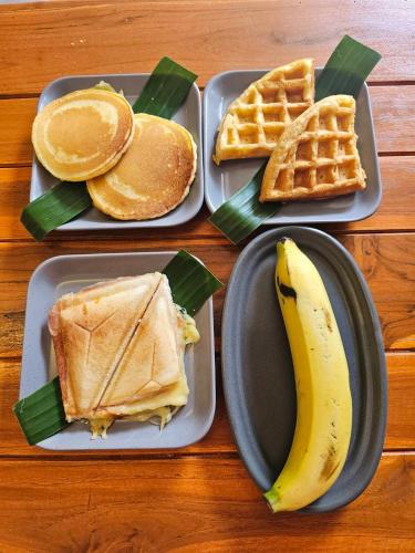 three plates of food with a sandwich and waffles and a banana at Life koh tao resort in Koh Tao