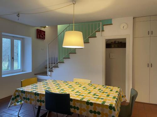 a dining room with a table and a staircase at Fuga nella Natura - Rustico a pochi minuti dal lago di Lugano in Cuasso Al Monte