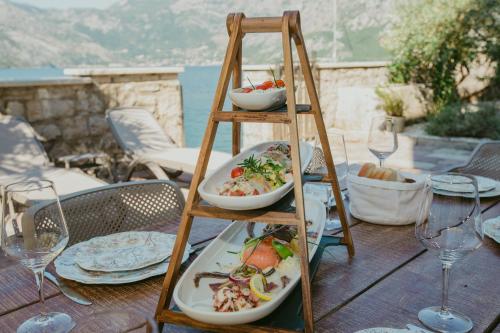 a wooden shelf with plates of food on a table at Villa Toma in Donji Morinj
