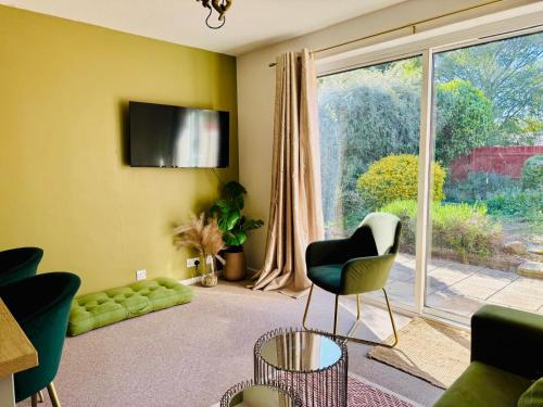 a living room with a couch and a tv on the wall at JADE - Cambridge Rental with Garden and BBQ, Near City Centre in Cambridge