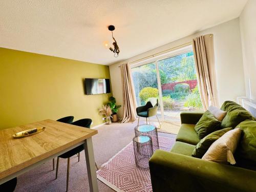 a living room with a green couch and a table at JADE - Cambridge Rental with Garden and BBQ, Near City Centre in Cambridge