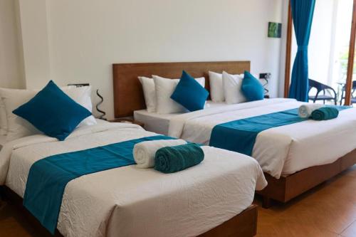 three beds in a room with blue and white at The Palms Thoddoo in Thoddoo