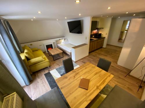 a living room with a table and a yellow couch at GRUBERS, Hotel Appartments Gastein in Bad Gastein