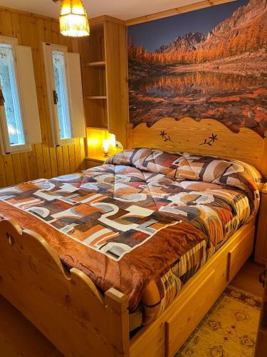 a bedroom with a wooden bed with a painting on the wall at I Larici - Appartamento per sognare in Alpe Devero