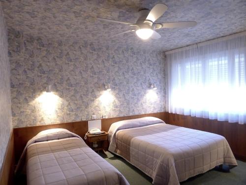 a bedroom with two beds and a ceiling fan at Hôtel du Sablar in Mont-de-Marsan