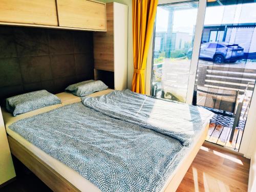 a bed in a room with a large window at Izzi Mobile Home - Terra Park SpiritoS in Kolan