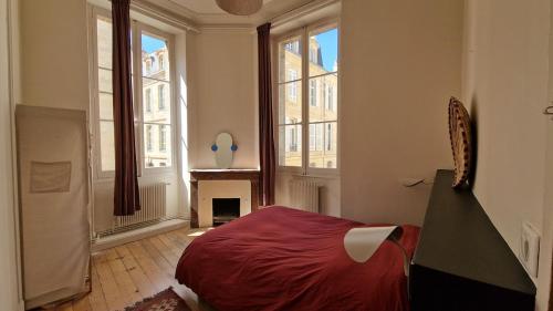 - une chambre avec un lit rouge dans une pièce dotée de fenêtres dans l'établissement St Michel 3 bedrooms appartment, à Bordeaux