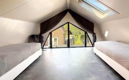 two beds in a room with a window at 't Boschhuys by Droomvilla in Bergen