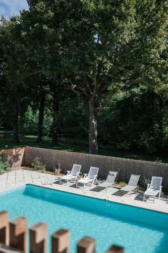 un groupe de chaises assises à côté d'une piscine dans l'établissement Maison Dharma à 5km de la plage avec Sauna, à Mimizan