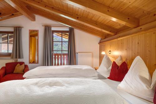 a bedroom with a large white bed and a red chair at Prackfolerhof in Fie allo Sciliar