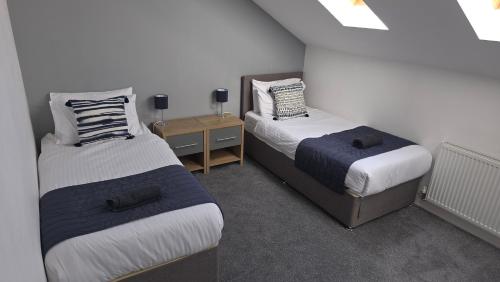 Habitación con 2 camas y mesita de noche con 2 camas Sidx Sidx en 4 Bedroom Home Tameside Greater Manchester Sleeps 8, en Mánchester