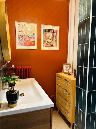 une salle de bain avec un mur orange et un lavabo blanc dans l'établissement Nid doux, au Mans