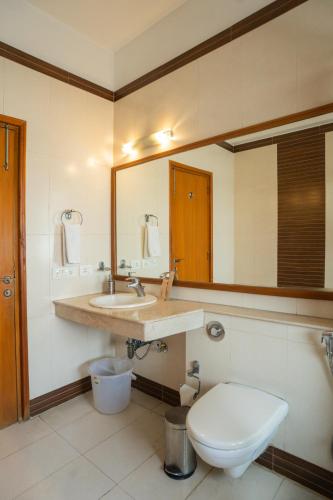 a bathroom with a toilet and a sink and a mirror at Ahuja Residency Cyber City I in Gurgaon