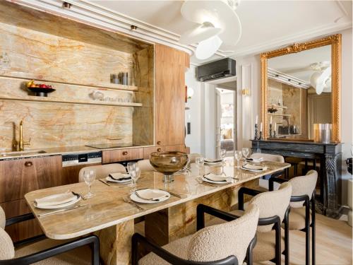 une salle à manger avec une grande table et des chaises en bois dans l'établissement Merveil - Signature Suite - Opera - Rougemont III, à Paris