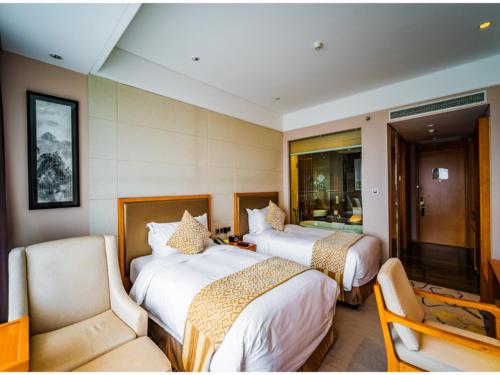 a hotel room with two beds and a chair at Suzhou Qingshan Conference Center in Suzhou