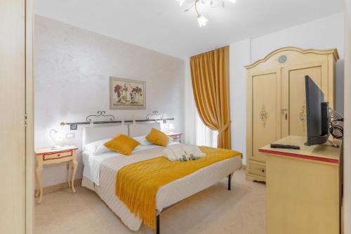 een slaapkamer met een bed met gele lakens en een televisie bij Casa Royale al Relais Du Lac in Desenzano del Garda