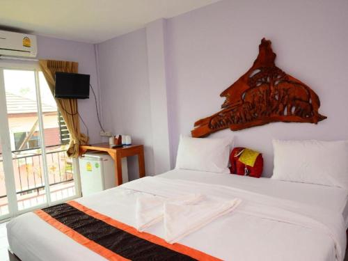 a bedroom with a white bed with a wooden headboard at Baan Taklom Chomtalay in Ban Sahakham