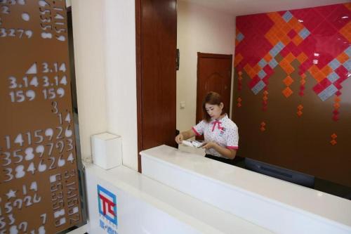 a woman is standing in front of a mirror at PAI Hotels·Shijiazhuang Development Zone Tianshan Science and Technology Park in Shijiazhuang