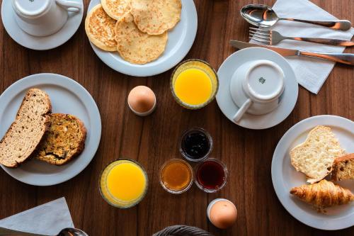 a table topped with plates of breakfast foods and eggs at Eden Park Hotel Restaurant in Pont-lʼÉvêque