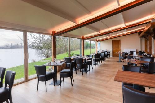 a dining room with tables and chairs and large windows at Eden Park Hotel Restaurant in Pont-lʼÉvêque