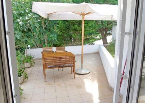 a table and chairs under an umbrella on a patio at Apartments Vlado in Njivice