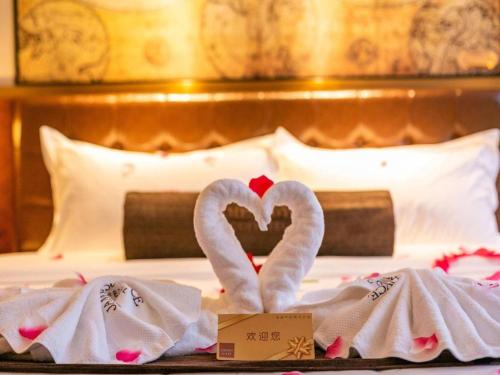two towels in the shape of hearts on a bed at James Joyce Coffetel Chengdou Wuqing Wanda Plaza in Chengdu